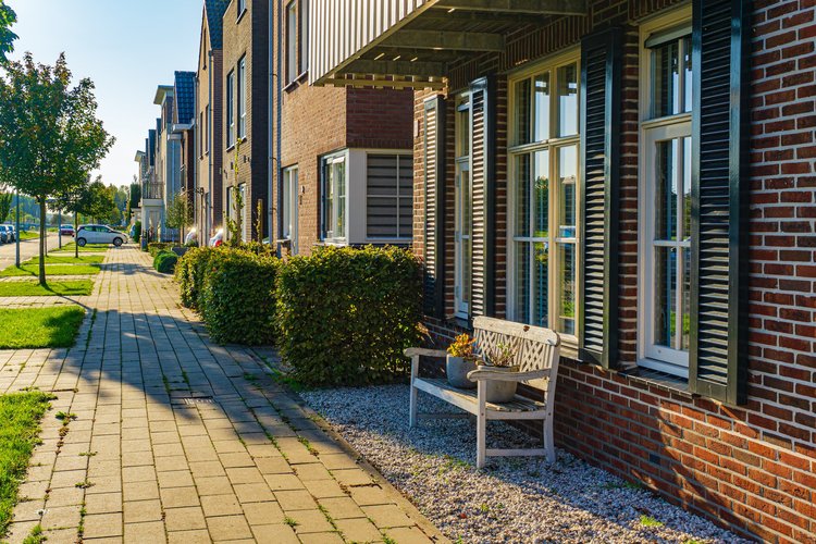 A bench in front of a row of three-story brick homes.